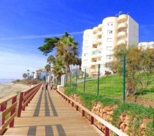 a wooden boardwalk next to a beach with a building at Apartamento Playa Algaida in Sitio de Calahonda