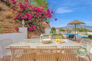 a patio with a table and chairs and pink flowers at Casa del Barco Villa with Private Retreat Vibes in Guaro
