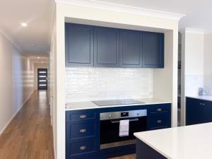 a kitchen with blue cabinets and a white counter top at Eliza's Escape 1 Wagga CBD in Wagga Wagga