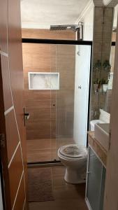 a bathroom with a toilet and a glass door at Marina Clube in São Pedro da Aldeia