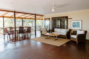 un soggiorno con un divano, sedie e un tavolo di Wybalena ocean views tropical big home garden pool a Port Douglas