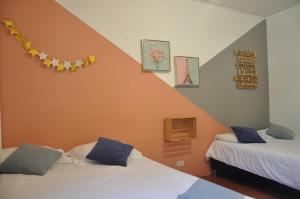 two beds in a room with an orange wall at Laureles, casa completa y amplia para grupos grandes in Medellín