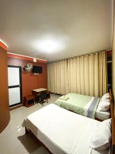 a hotel room with two beds and a desk at Hotel Auka's in Aucayacu