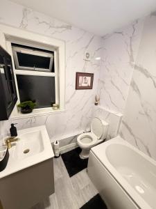 a white bathroom with a toilet and a sink at The Royal Hue 4bed house close to city centre in CBG +16 photos