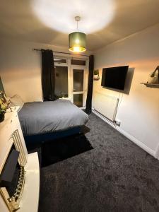 a bedroom with a bed and a flat screen tv at The Royal Hue 4bed house close to city centre in CBG