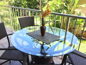 a glass table with a flower in a vase on a patio at Kihei Beach Condo, Romantic Kamaole II in Kihei