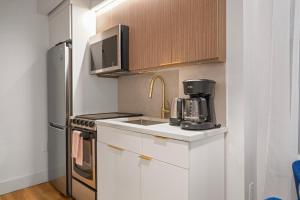 una cucina con mobili bianchi e un frigorifero di Comfortable 2BD Unit in Manhattan a New York