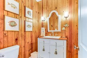 a bathroom with wooden walls and a sink and a mirror at Tenth Street Retreat in Tybee Island +51 photos
