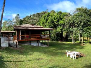 a house with two white chairs in the grass at Chalés Aguas Serenas in Santo Antônio do Pinhal