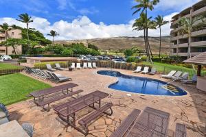 a patio with two picnic tables and a swimming pool at Island Sands 210 · IS 210 OceanFront Condo Expansive Ocean Views in Maalaea