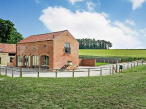 Un edificio de ladrillo con una valla al lado de un campo. en 3 Bed in Malton 75898, en Amotherby