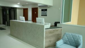 a lobby with two laptops on a counter with a chair at Mont Blanc Suites Duque de Caxias in Duque de Caxias