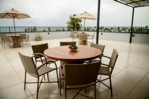 una mesa de madera y sillas con sombrillas en el patio en Apto Pet Friendly com Piscina a 100m da Orla, en São Bento