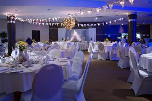un salón de banquetes con mesas y sillas blancas y una lámpara de araña en Hotel Universel Alma en Alma