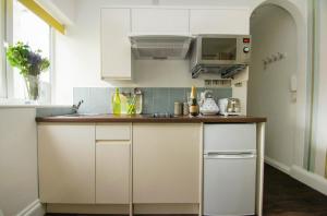 eine Küche mit weißen Schränken und einer Theke in der Unterkunft Between Piers - Central- by Brighton Holiday Lets in Brighton & Hove