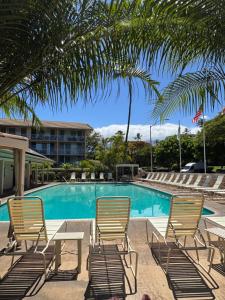 a pool with chairs and a table and palm trees at Kihei Beach Condo, Romantic Kamaole II in Kihei +22 photos