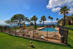 Una valla alrededor de una piscina con palmeras. en Napili Point A8 · NP A8 OceanFront 1BD Condo w Ocean Views AC Po, en Kahana