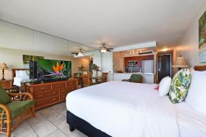 a bedroom with a large white bed and a television at Mahana 602 · MA 602 Kaanapali OceanFront Studio Ocean View Pool in Kahana +56 photos