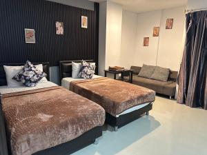 a hotel room with two beds and a couch at Happy Fish Guesthouse in Patong Beach