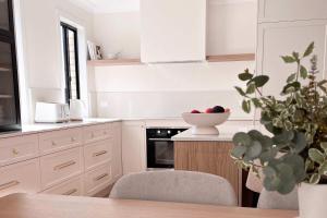 a kitchen with white cabinets and a bowl of apples on the counter at Luxury 3-Bed Family Retreat Office Kayaks & Yard in Marsden