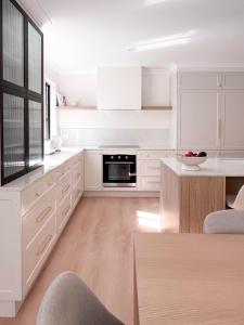 a white kitchen with white cabinets and a table at Luxury 3-Bed Family Retreat Office Kayaks & Yard in Marsden