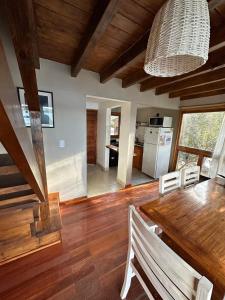 a dining room with a wooden table and a kitchen at Cabañas ROCA DEL LAGO, en Villa Pehuenia in Aluminé
