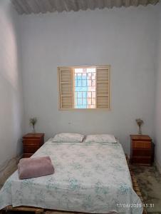 a white bedroom with a bed and a window at Casa Baunilha in Cavalcante