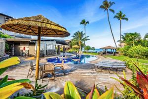 a resort with a swimming pool and an umbrella at Ocean Views & ac! ks d8 - Sullivan Properties in Kahana