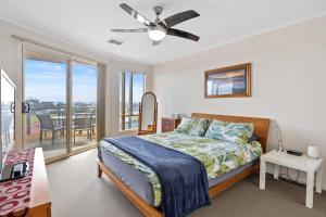 a bedroom with a bed with a ceiling fan and a balcony at Baywatch - 8 James Drive, Carrickalinga in Carrickalinga