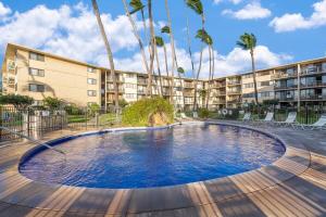 a swimming pool in front of a building with palm trees at Kanai A Nalu 211 · KAN 211 Remodeled OceanFront 2BD for Whale Wa in Wailuku