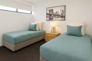 a bedroom with two beds and a night stand with a lamp at Home to Holiday at Central Islington Apartments in Townsville