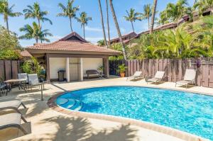 a swimming pool with chairs and a house with palm trees at Kihei Resort 202 · KRS 202 Family Getaway 2BD w AC Pool Beach in Kihei