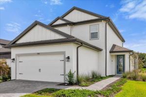 a white house with a garage at Luxury e Themed Rooms Minutes from Disney Parks in Kissimmee