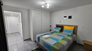 a bedroom with a bed with colorful pillows on it at Les cocotiers d'Aladya in Lamentin +44 photos