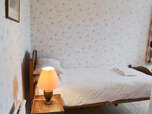 1 dormitorio con 1 cama con lámpara en una mesa en Windways, en Port Erin 1 foto más