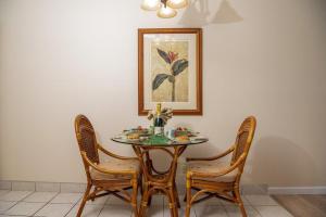 a dining room table with four chairs and a picture at Kulakane 105 · KK105 Sunsets Ocean Views Oceanfront in West Maui in Kahana