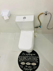 a bathroom with a white toilet with a sign on the floor at Pamito Sunny Paradise in Diani in Diani Beach