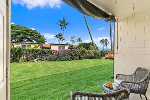 een terras met twee stoelen en een gazon met palmbomen bij Napili Ridge A2 · NR A2 Napili Condo Near Beaches Away From Crow in Kahana