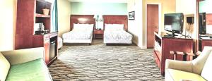 a hotel room with two beds and a television at Brunswick Suites Golden Isles Gateway I-95 in Brunswick