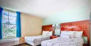 a hotel room with two beds and a window at Brunswick Suites Golden Isles Gateway I-95 in Brunswick