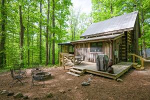 a cabin in the woods with a deck and a grill at Honeymoon Cabin in McEwen