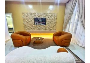 Una sala de estar con dos sillas y un televisor. en Zeeshortlet Apartment, en Lekki