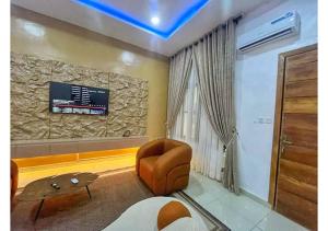 Una sala de estar con un sofá y un televisor en una pared. en Zeeshortlet Apartment, en Lekki
