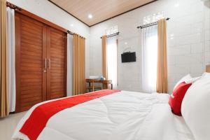 a bedroom with a large white bed with red pillows at RedDoorz at Pondok Kampung Harmony Ubud in Ubud