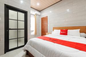 a bedroom with a large white bed with red pillows at RedDoorz at Pondok Kampung Harmony Ubud in Ubud