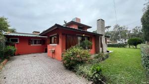 una casa roja con una pasarela de ladrillo delante de ella en Santa Clara Mar, en Frente Mar