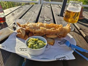 une assiette de nourriture avec du fish and chips et un verre de bière dans l'établissement Modern Newly Renovated Home on the Broads, à Lowestoft