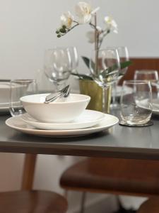 a table with a white bowl and plates and glasses at Centrally located 1bed near Windsor Castle Slough in Slough