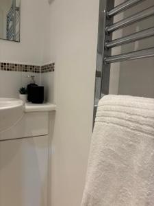 a white bathroom with a sink and a mirror at Centrally located 1bed near Windsor Castle Slough in Slough
