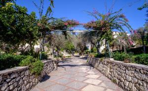 a stone walkway with a stone wall and flowering trees at Dalle Grotte al Mare in Fontane Bianche +16 photos